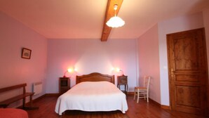 Un dormitorio con una cama de madera, dos mesitas de noche con lámparas, una silla de madera y una puerta de madera.
