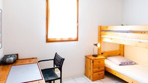 A small, tidy room with a bunk bed, a desk with a chair, a small nightstand with a lamp, and a framed picture on the wall. - Air-conditioned 3-Room Pavilion with Terrace, Parking, and Wi-Fi - Sleeps 4 (Narbonne-Narbonne Plage-Narbonne Plage)
