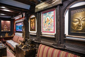 A traditional room with a wooden bench, framed artwork, and religious statues. - Nepal Pavilion Inn (Kathmandu)