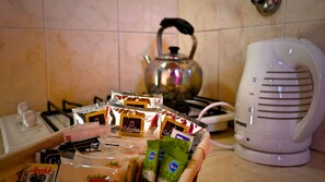Una encimera de cocina con diferentes alimentos, una tetera y una tetera eléctrica blanca.