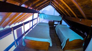 Un dormitorio con dos literas de madera, techo de madera y una ventana al final de la habitación.