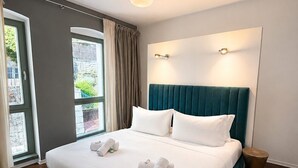 Een hotelkamer met een bed, een raam, een deur en een klein rond tafeltje.