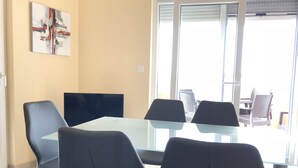A conference room with a glass table and black chairs, a painting on the wall, and a view through the glass door. - Atrium Novalja (Novalja)