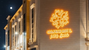 The exterior of the Gulanar Hotel with a glowing neon sign. - Julnar Hotel (Unaizah)