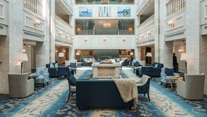 A spacious lobby with a central seating area, multiple levels, and a chandelier. - Julnar Hotel (Unaizah)