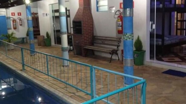 A pool area with a tiled floor, a blue railing, and a bench. - Pousada Recanto Dom Lázaro (Cesario Lange)