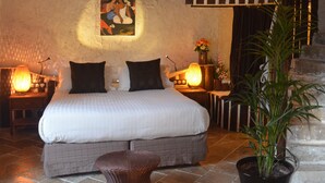 Ein Schlafzimmer mit Bett, Nachttischlampen, einem Gemälde, einer Treppe und einer Zimmerpflanze.