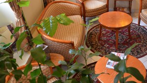 Ein gemütliches Zimmer mit Korbstühlen, einem runden Tisch und einem gemusterten Teppich.