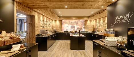 A modern kitchen with wooden ceiling, black countertops, and a central island with a coffee machine.