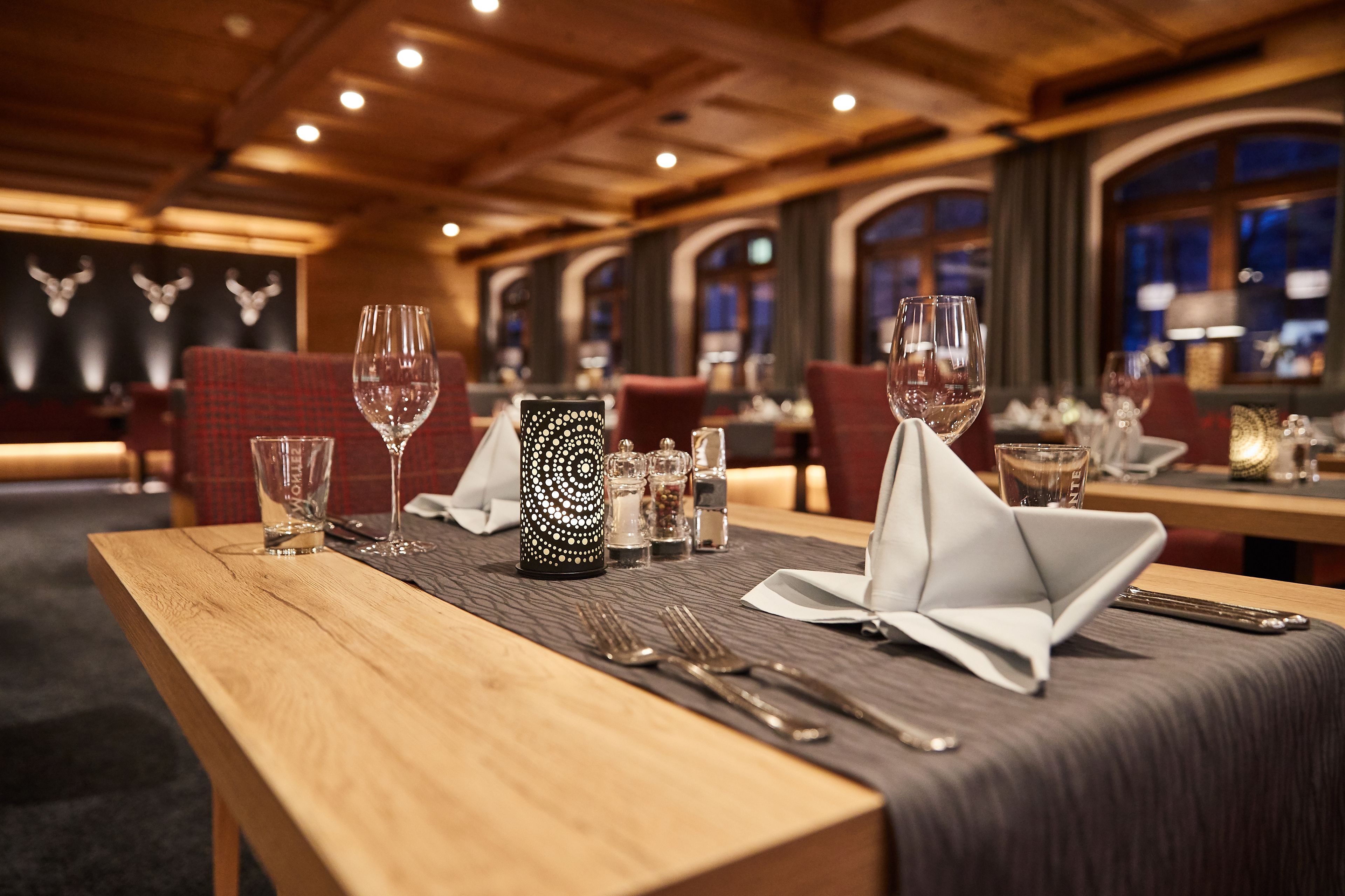 A restaurant setting with wooden tables, red upholstered chairs, and a patterned centerpiece.