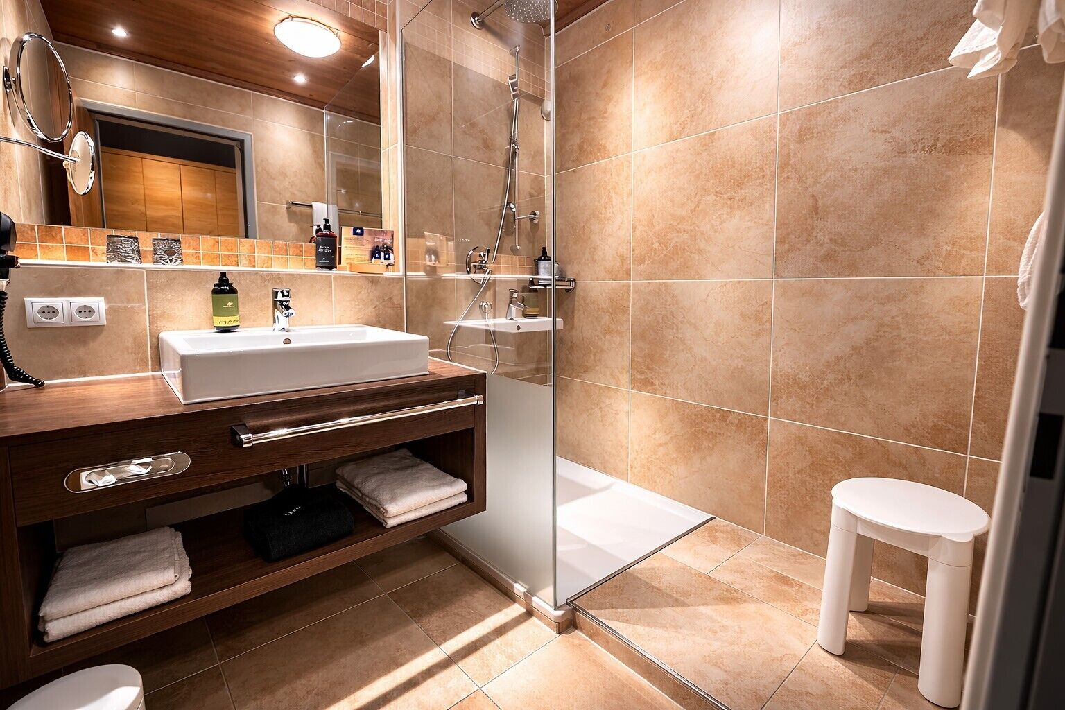 Un baño moderno con un espejo grande, un lavabo, una ducha y un inodoro.