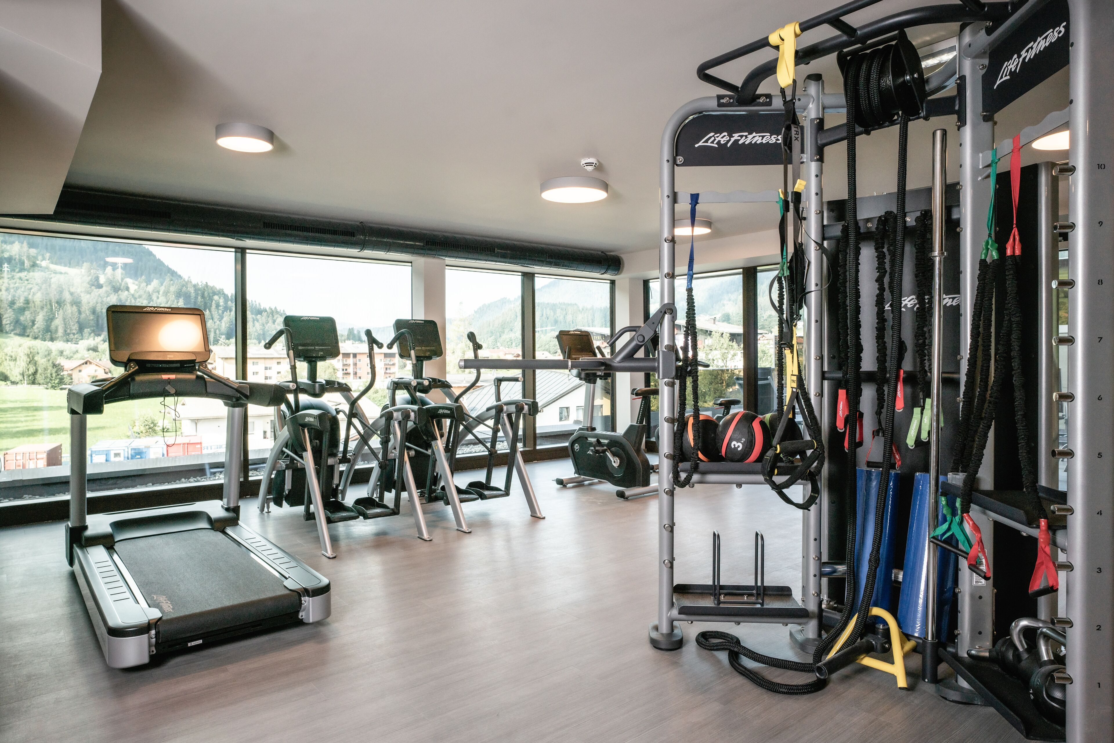A gym with treadmills, elliptical machines, and a weightlifting station.