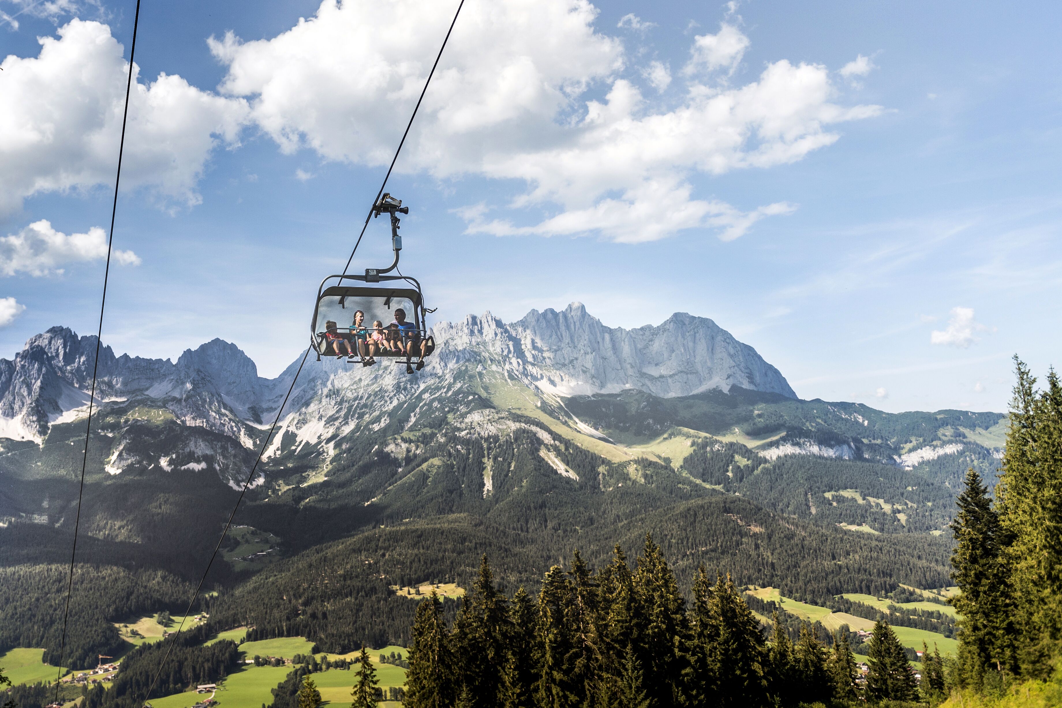 A cable car with passengers ascending a mountain.