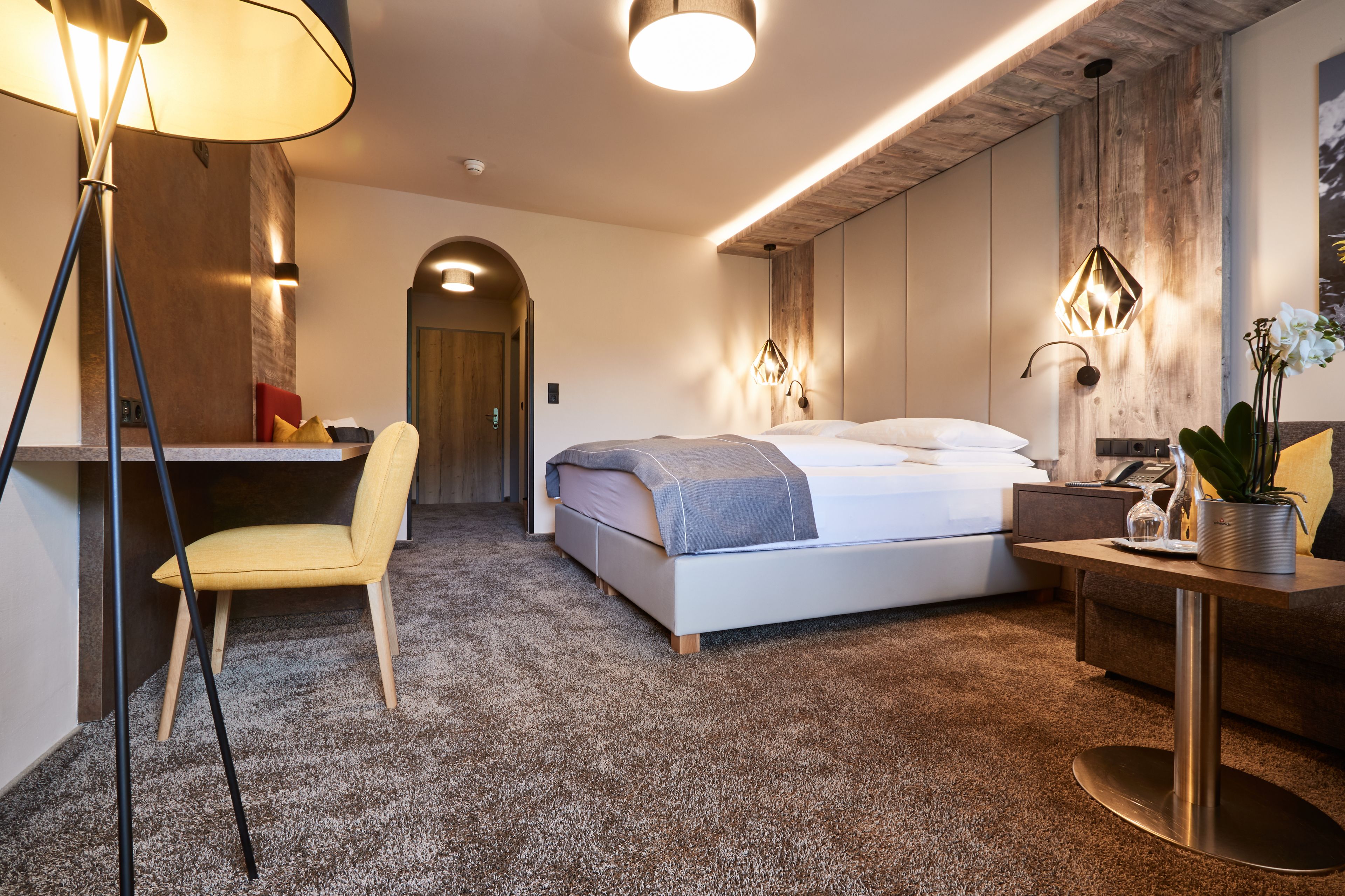 Una camera d'hotel moderna con un letto grande, una scrivania, una sedia e un tavolino.