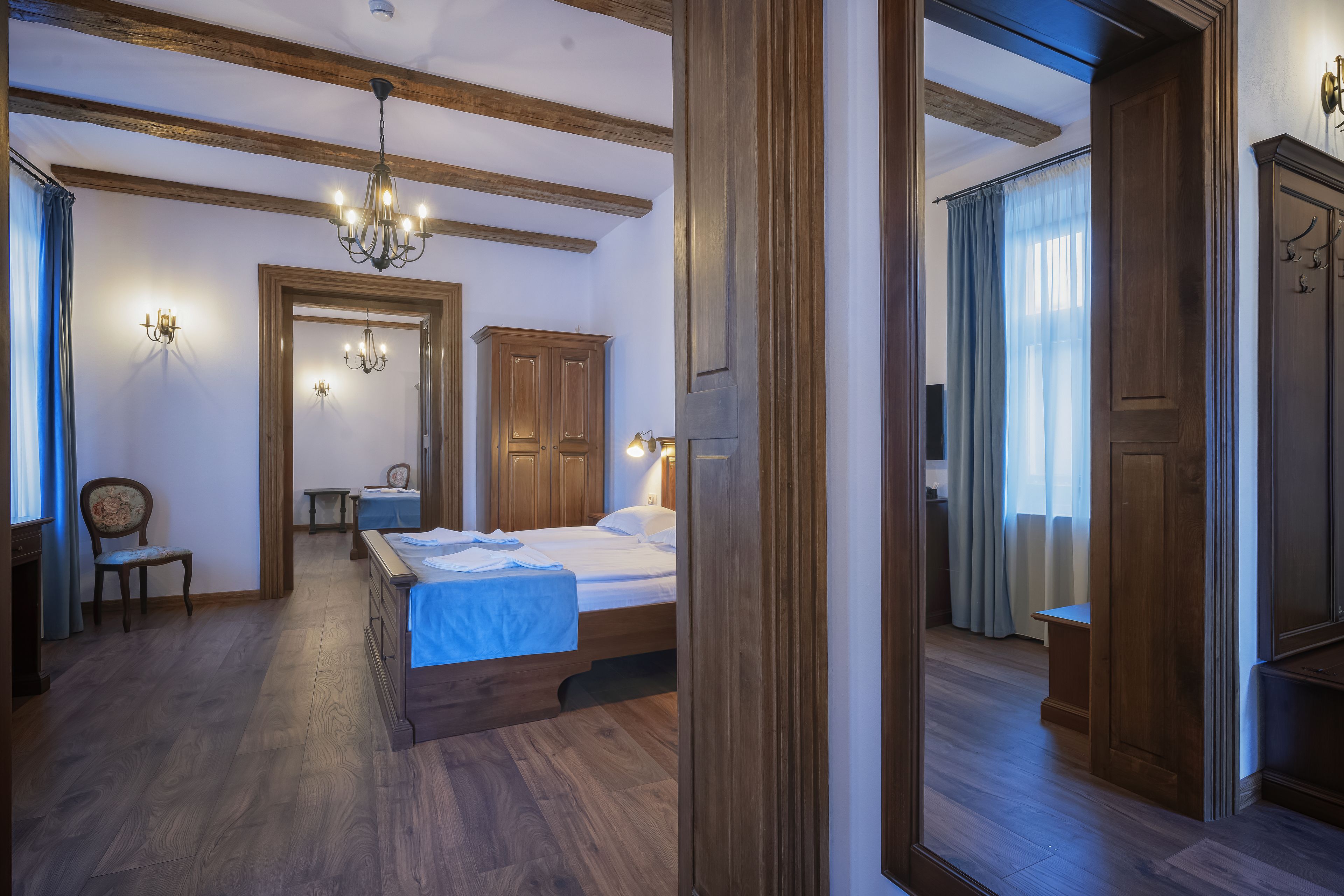 A hotel room with a wooden bed, a chair, a desk, and a wardrobe.