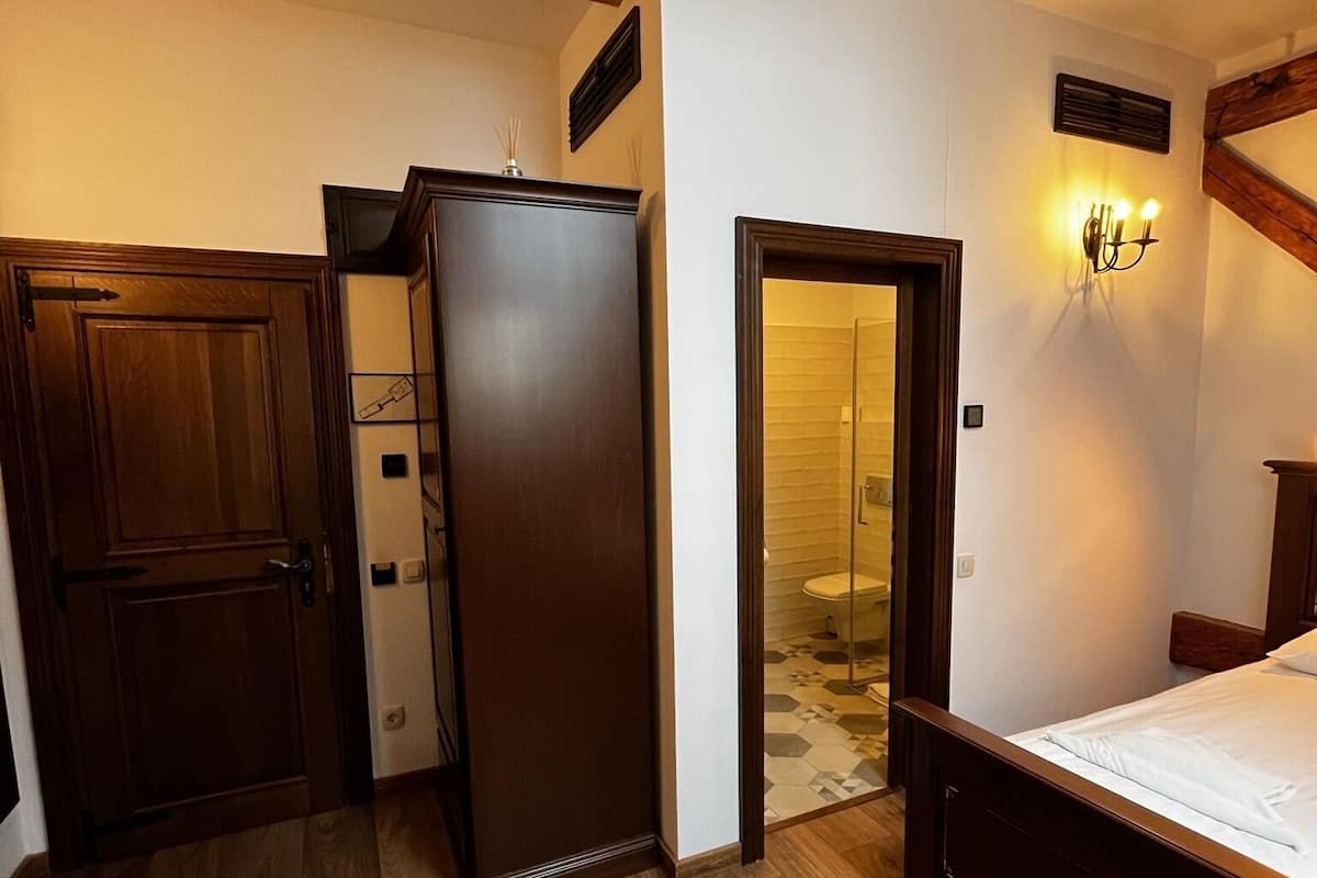 Quarto com piso de madeira, uma cama, um guarda-roupa e uma porta para o banheiro.