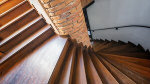 Un escalier en colimaçon avec des marches en bois et un pilier en briques.