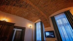 Une pièce avec un plafond en briques, des meubles en bois, un téléviseur et une fenêtre avec des rideaux.
