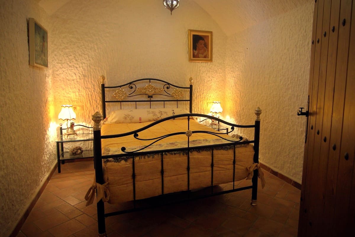 Une chambre à coucher avec un lit, deux lampes de chevet, un tableau au mur et une porte.