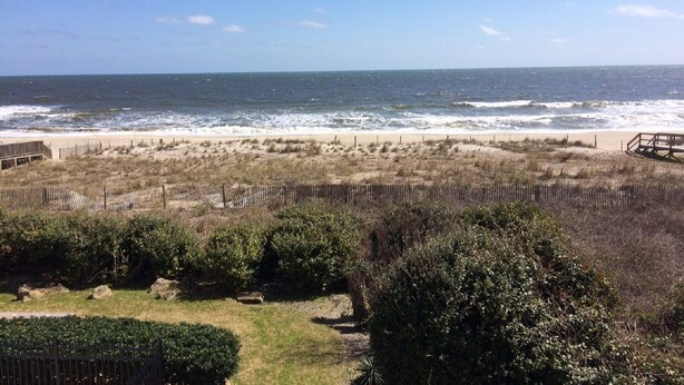 A beach view with a wooden boardwalk, sandy beach, and ocean waves. - Stunning ocean front condo with an extraordinary view of the Fabulous Boardwalk! (Carolina Beach)
