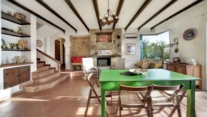 A spacious kitchen with a green table, wooden chairs, and a stone fireplace. - House / Villa - Marina di Ragusa, Ragusa (Marina di Ragusa)