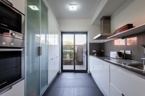 A modern kitchen with a Bosch oven, a glass door pantry, and a view to the outside. - L'Orangerie (Vilamoura)