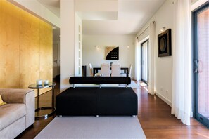 A modern living room with a sofa, a coffee table, and a dining area with chairs and a table. - L'Orangerie (Vilamoura)