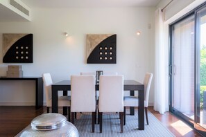 A modern dining area with a rectangular table, six chairs, and two abstract wall art pieces. - L'Orangerie (Vilamoura)