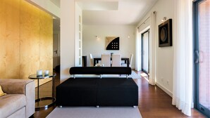 A modern living room with a sofa, a coffee table, and a dining area with chairs and a table.