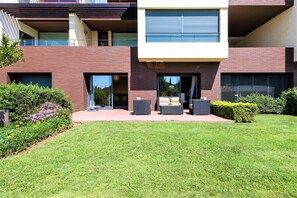 A modern two-story house with a well-maintained lawn, outdoor seating area, and large windows. - L'Orangerie (Vilamoura)