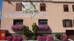 Un edificio con el letrero "RISTORANTE ANNA" y macetas con flores en los alféizares de las ventanas.
