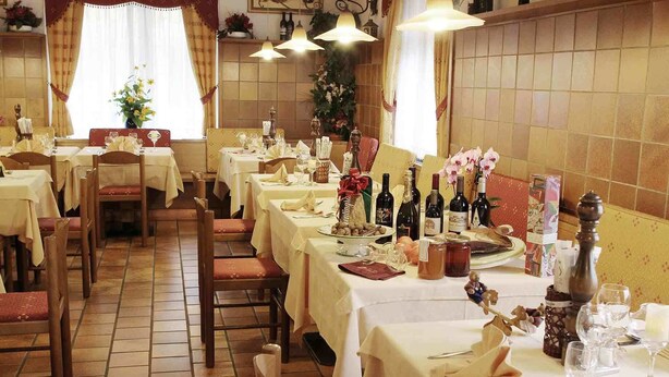 Un restaurante con varias mesas dispuestas para comer, cada una con manteles blancos y diversos platos y bebidas.