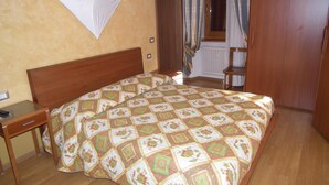 Un dormitorio con una cama de madera, una mesita de noche, una silla y una ventana con cortinas.