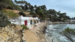 A coastal walkway with a stone path leading to a white building with colorful doors, overlooking the sea. - Large, Luxury Villa, Sea Views, Heated Pool in Begur, Costa Brava (La Borna)