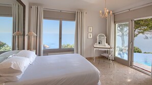 A bedroom with a large bed, a desk, and a view of the sea. - Large, Luxury Villa, Sea Views, Heated Pool in Begur, Costa Brava (La Borna)