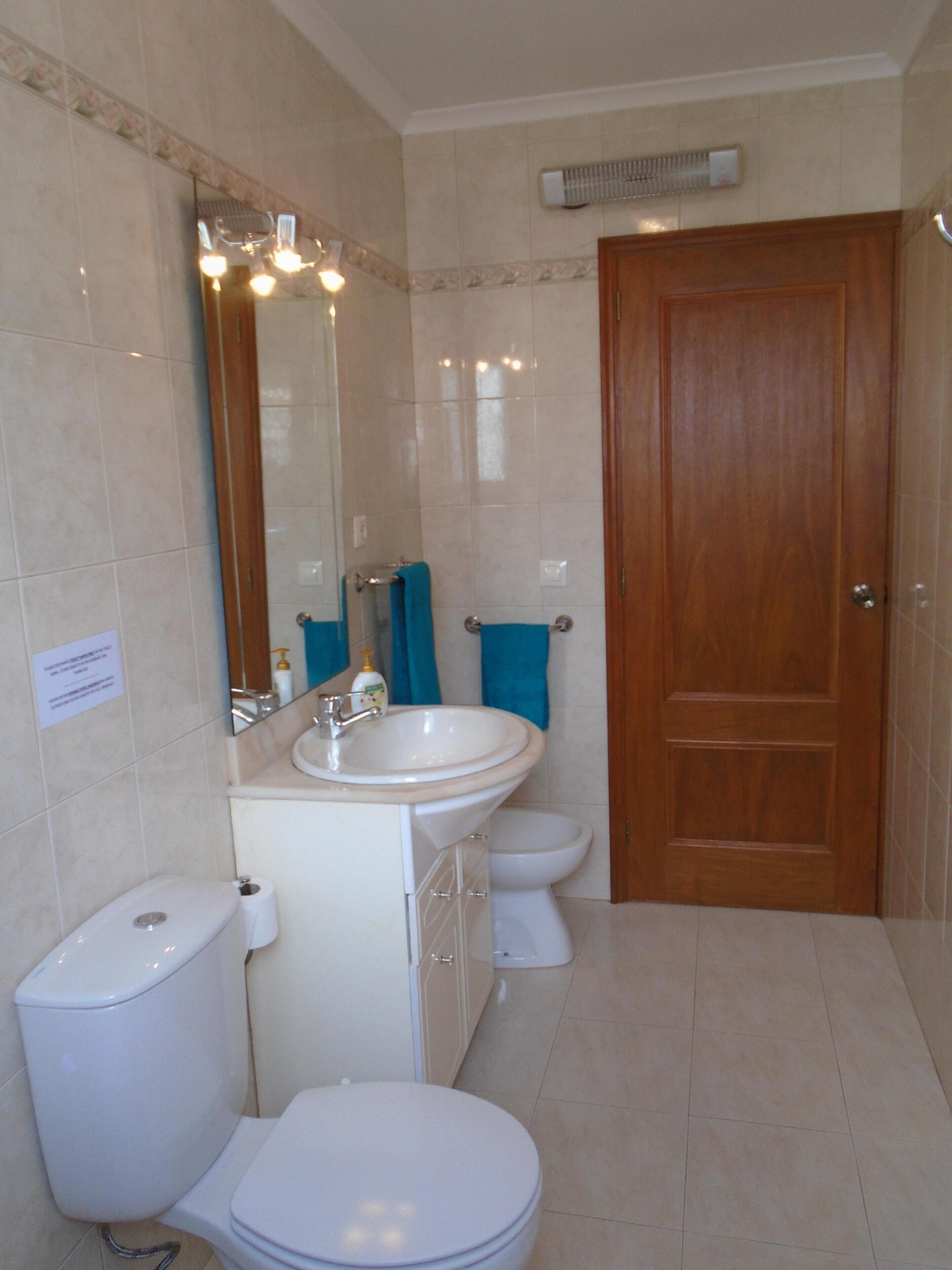 A bathroom with a toilet, sink, and mirror.