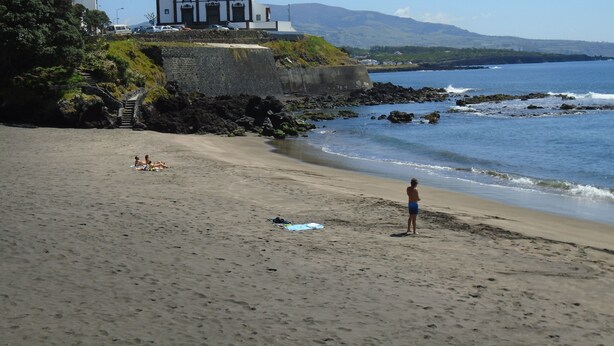 A beach with a church, rocky shoreline, and a person standing on the sand. - Casa Nuno e Lorena - Ideal location and privacy. (Sao Roque)