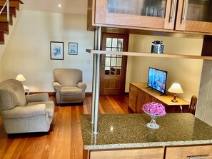 A living room with a sofa, a chair, a TV, and a small table with a lamp.