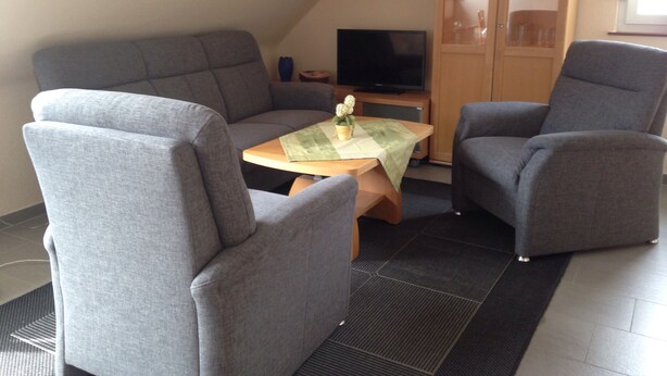 A cozy living area with a sofa, two armchairs, a small table, and a television. - Vacation apartment for 2 -3 persons in the beautiful Weserbergland (Hessisch Oldendorf)