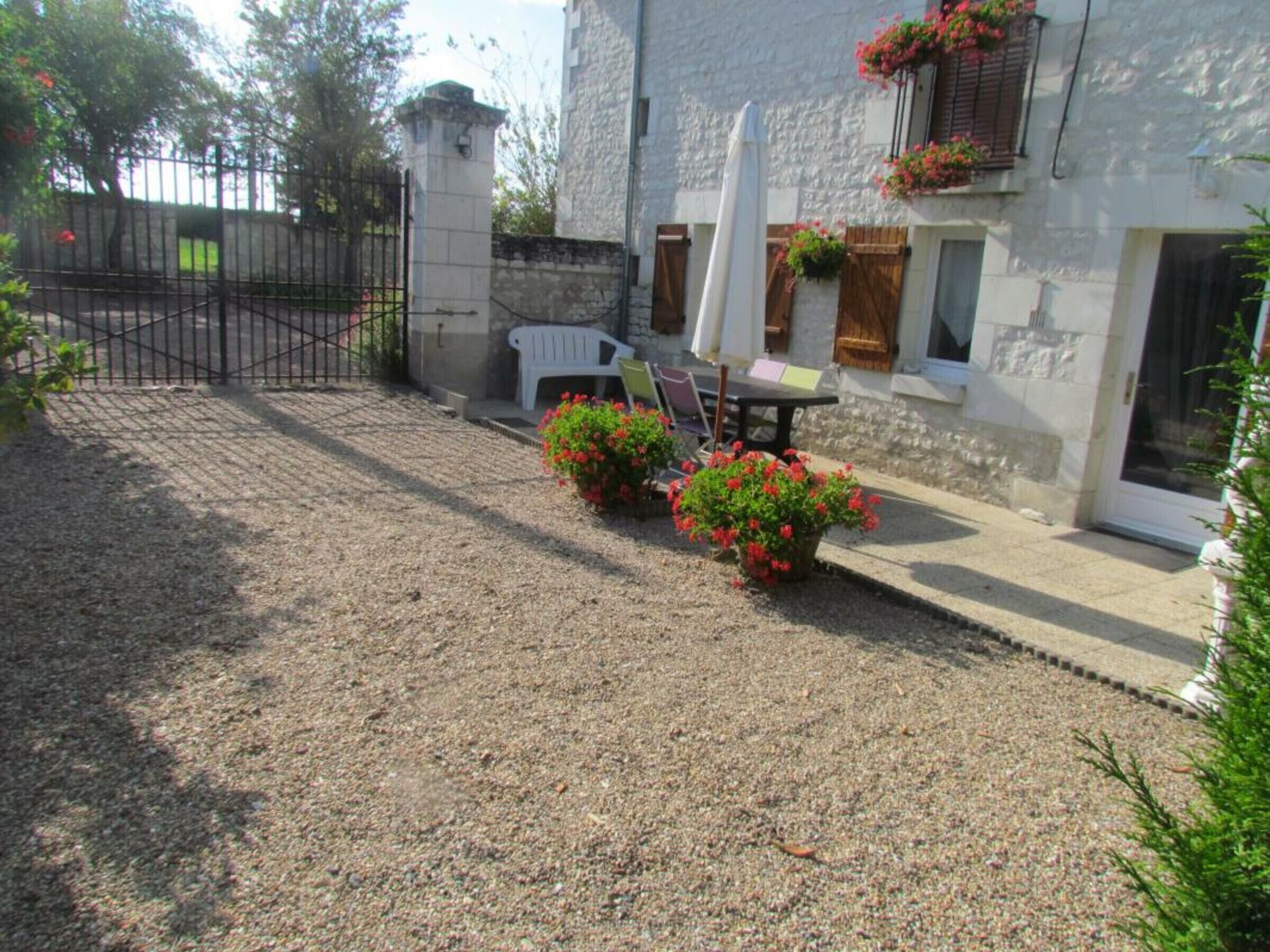 A courtyard with a gravel path, a table with chairs, and potted plants.