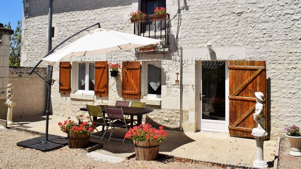 A rustic stone building with a balcony, outdoor seating, and a wooden door. - Quiet 40m² cottage with private courtyard (La Tour-Saint-Gelin)