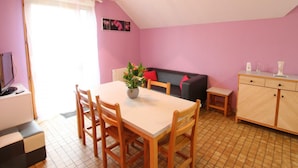 Une pièce confortable avec une table à manger, des chaises, un canapé et un buffet.