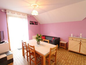 Een knus ingerichte kamer met een eettafel, stoelen, een bank en een kast.
