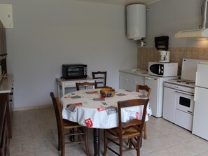 A compact kitchen with a dining table, chairs, a microwave, a toaster, a kettle, and a stove. - Quiet 3-room house near the beach in La Brée-les-Bains (La Brée-les-Bains)