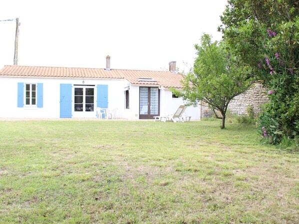 A house with a tiled roof, a small front yard, and a tree with purple flowers. - Quiet 3-room house near the beach in La Brée-les-Bains (La Brée-les-Bains)
