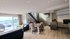 Un espacio habitable moderno con comedor, cocina y una escalera que sube a un nivel superior.