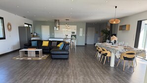 A modern living room with a sofa, coffee table, and dining area with chairs and a table set for a meal. - Contemporary wine estate villa with infinity pool (Servian)