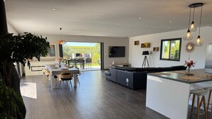 A modern kitchen with a dining area, a large island, and a TV mounted on the wall. - Contemporary wine estate villa with infinity pool (Servian)