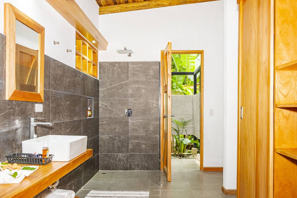 Une salle de bain avec un lavabo blanc, des carreaux de marbre foncé et des éléments décoratifs en bois.