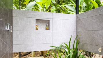 A modern bathroom with a built-in shower and two bottles of shampoo in a shelf.